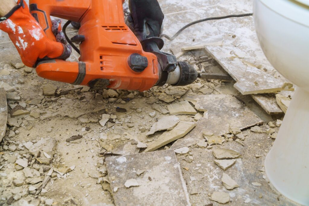 Demolition of old tiles with jackhammer. Renovation of removes old tiles from floor